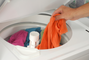 Person adding clothing to a washing machine