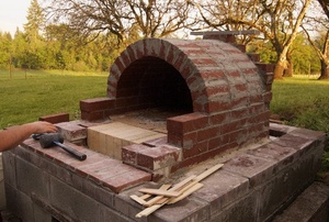 The construction of an outdoor brick pizza oven.