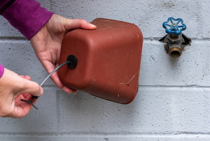 hands applying a faucet cover to protect from frost