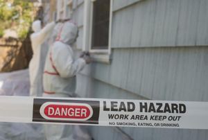 A tape with a lead hazard warning on it against a house.