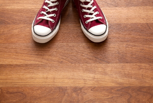 A pair of red sneakers on a wood floor. 