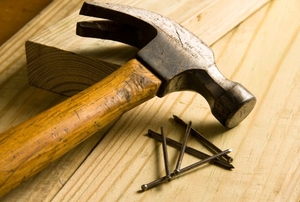 A hammer and nails sitting atop lumber pieces.