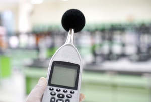 A woman holds a sound level meter.