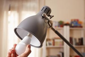 a lamp with someone putting in a lightbulb