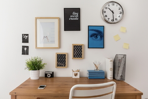 A gallery wall of art above a desk.