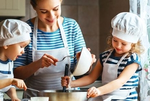 A woman and two kids cook.