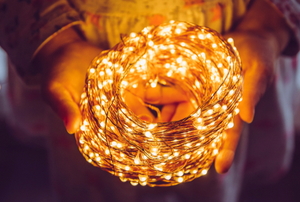 hands holding coiled and lit LED string lights