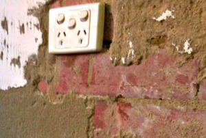 A brick wall with un-even broken plaster.