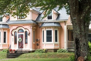 pink painted Victorian house with lawn and tree