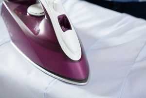 Ironing a shirt with a purple cased iron.