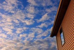 The side of a house and the cloudy sky above.