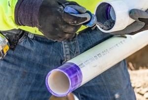 person clearing drain clog out of pvc piping with printed lettering