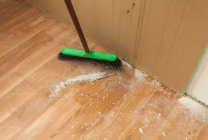 A broom sweeping up drywall dust.