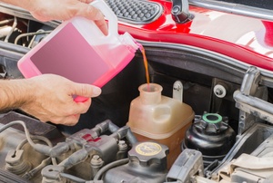 Someone pouring transmission fluid in a car.