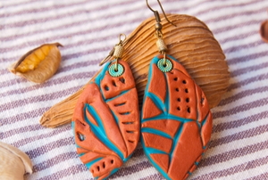 clay earrings on a striped fabric background with shells and leaves