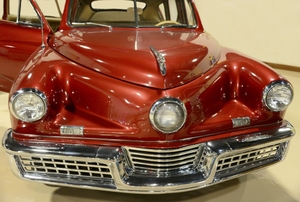a classic red car with large chrome bumper and zig-zag hood
