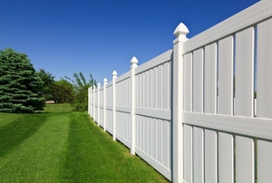 A white vinyl fence next to a newly-mowed yard.
