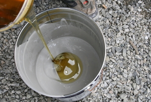 Mixing epoxy resin using two metal buckets.