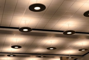 Rows of circular lamps hanging from a gray suspended ceiling.