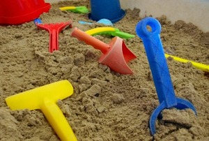 A sandbox full of plastic shovels and buckets.