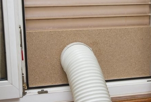 A portable AC exhaust hose fed through a window covering.