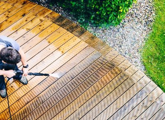 man washing deck with a pressure washer