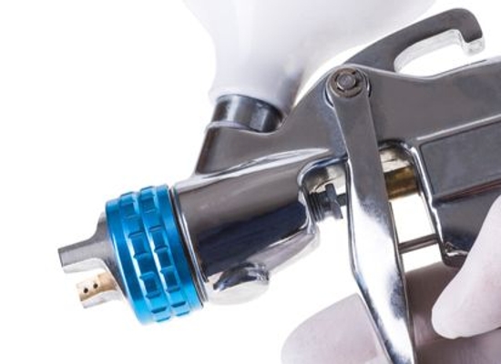 gloved hand holding paint spray device up close