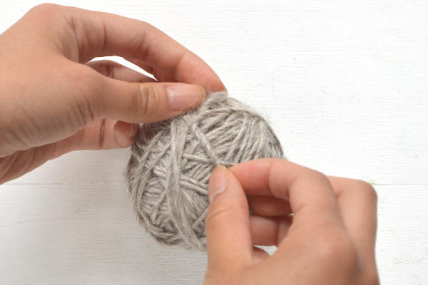 Tightly wrap the yarn around all your fingers, except your thumb, ten times. Mak