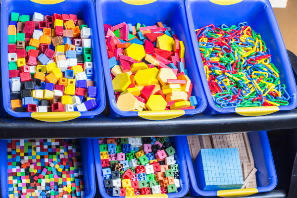 Building blocks and toys in rows of blue bins. 