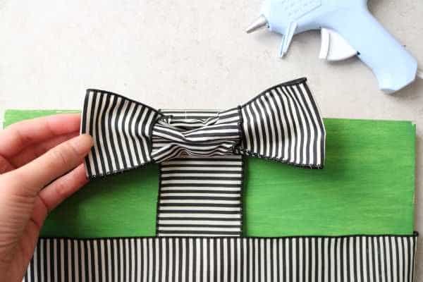A bow being attached to a green box. 