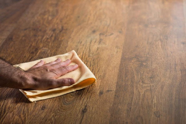 A hand rubbing a cloth on a wood floor. 