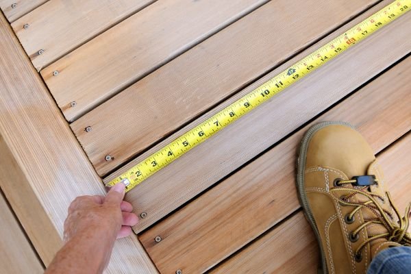 A wood deck with a measuring tape and a work boot in the corner.