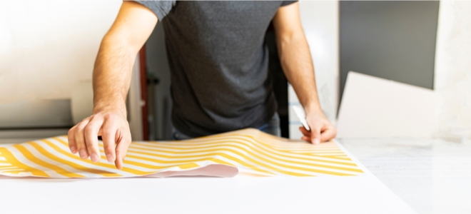 a man laying out striped temporary wallpaper