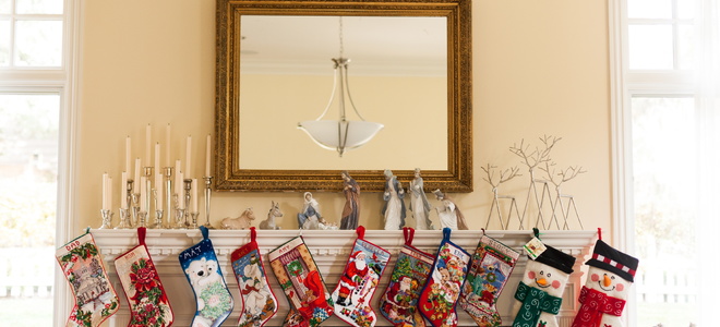 A mantel decorated with figurines and candle holders with stockings hanging in the front.