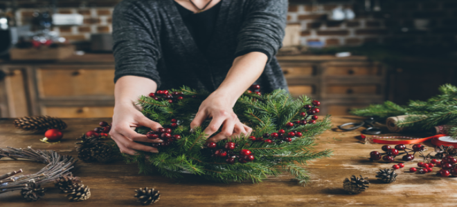 Someone adding berry springs to a DIY Christmas wreath.