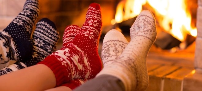 three pairs of feet in socks in front of a fire