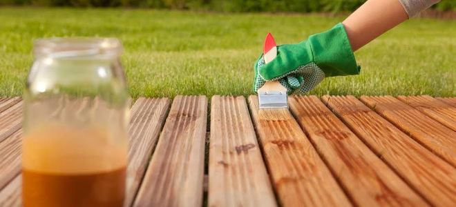 Gloved hand staining a deck