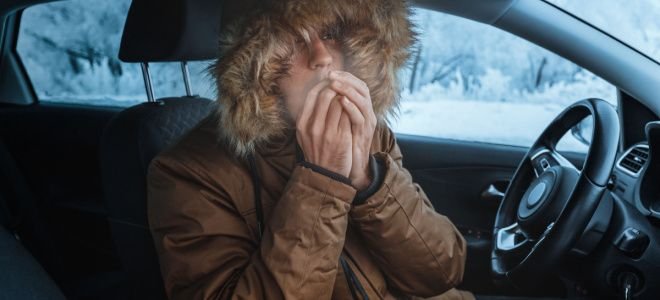 cold person in jacket in car blowing on hands