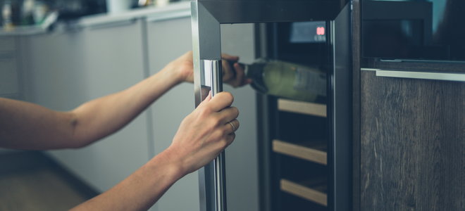 A woman opens a wine cooler.