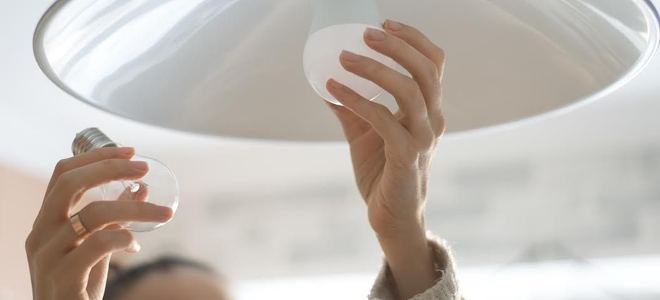 A woman installs a light bulb.