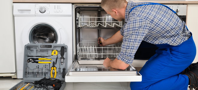 A man works on a dishwasher.