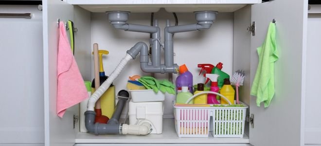 open cabinet under sink with cleaning supplies