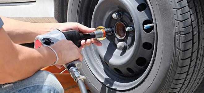 Someone working on a tire with a pneumatic nailer.