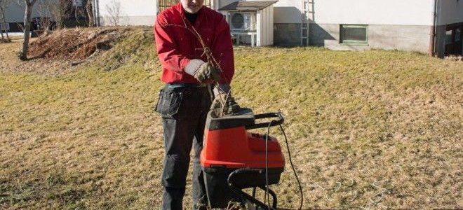 man feeding branches into a wood chipper