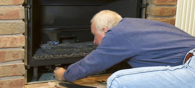 A man installing a fireplace insert. 