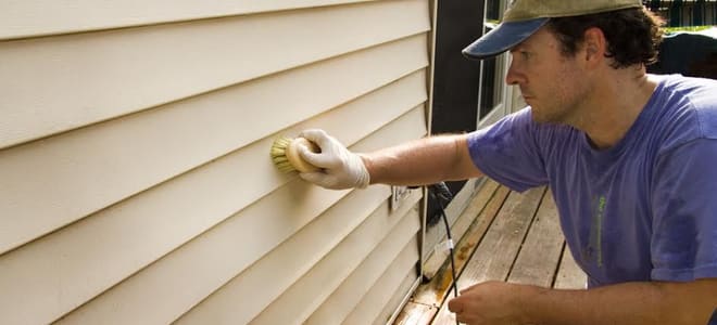 man cleaning siding with a brush