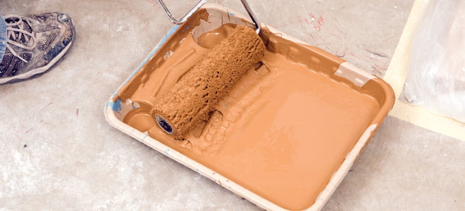 orange paint in a tray with a roller