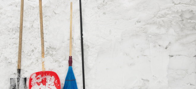 shovels and rakes leaning against a pile of snow
