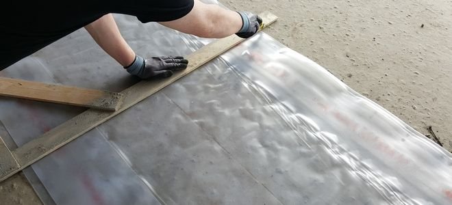hands cutting plastic sheeting along a wooden frame