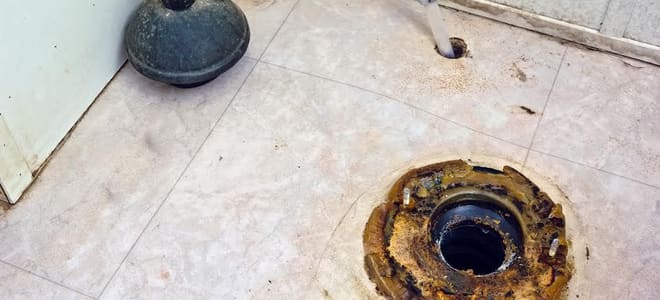 A rusted hole in the floor where a toilet should be. 